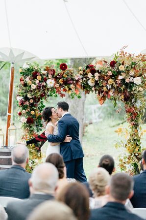 First Kiss Beneath a Chuppah Adorned with Fall Blooms and Leaves