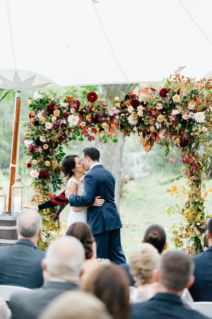 First Kiss Beneath a Chuppah Adorned with Fall Blooms and Leaves
