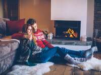 couple in holiday sweaters sitting by the fire