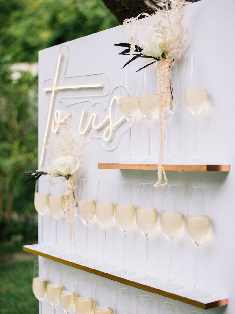 Champagne flute wall with neon sign at wedding reception