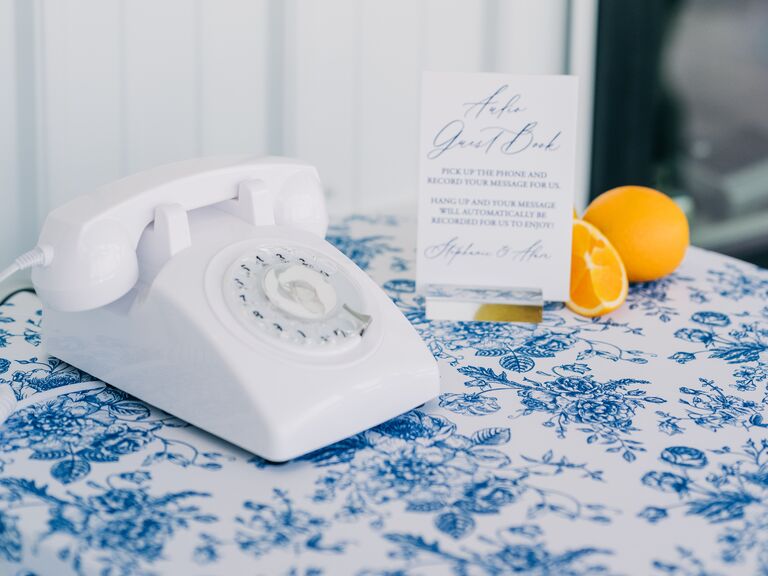 2023 wedding reception trend idea telephone wedding guest book with white vintage rotary phone on blue floral tablecloth