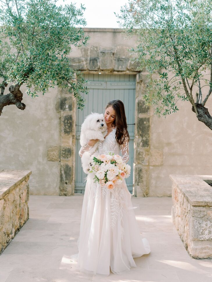 Bride Holding White Dog and Light, Neutrals Bouquet With Elegant Dress in Historic French Courtyard