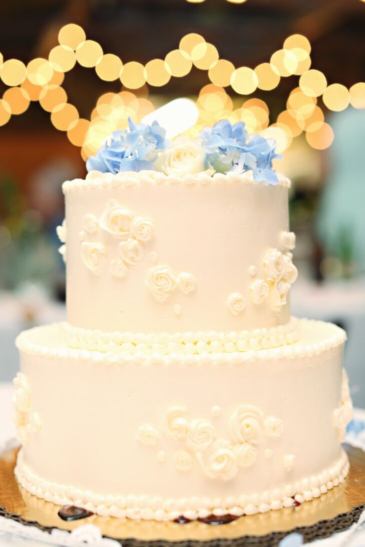 The couple had a small two-tier cake just for cutting, and then offered a cupcake buffet with 10 different flavors for guests. The cutting cake was iced in buttercream and topped with a few blue hydrangeas.