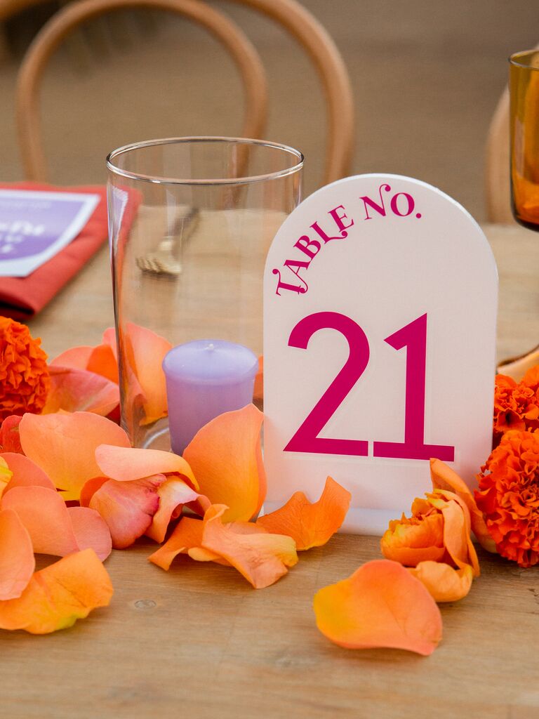 modern wedding table number with viva magenta text and orange rose petals on table