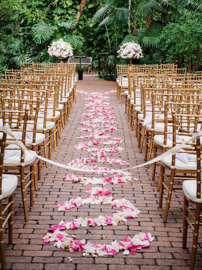 outdoor wedding ceremony venue with cobblestone aisle decorated with pink rose petals in swirled pattern