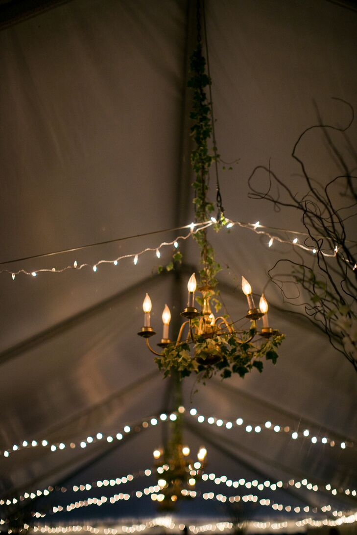Inside the reception tent at Woolverton Inn in Stockton, New Jersey, rows of string lights added whimsical ambiance. A number of chandeliers ran along the center of the tent and were decorated with ivy.