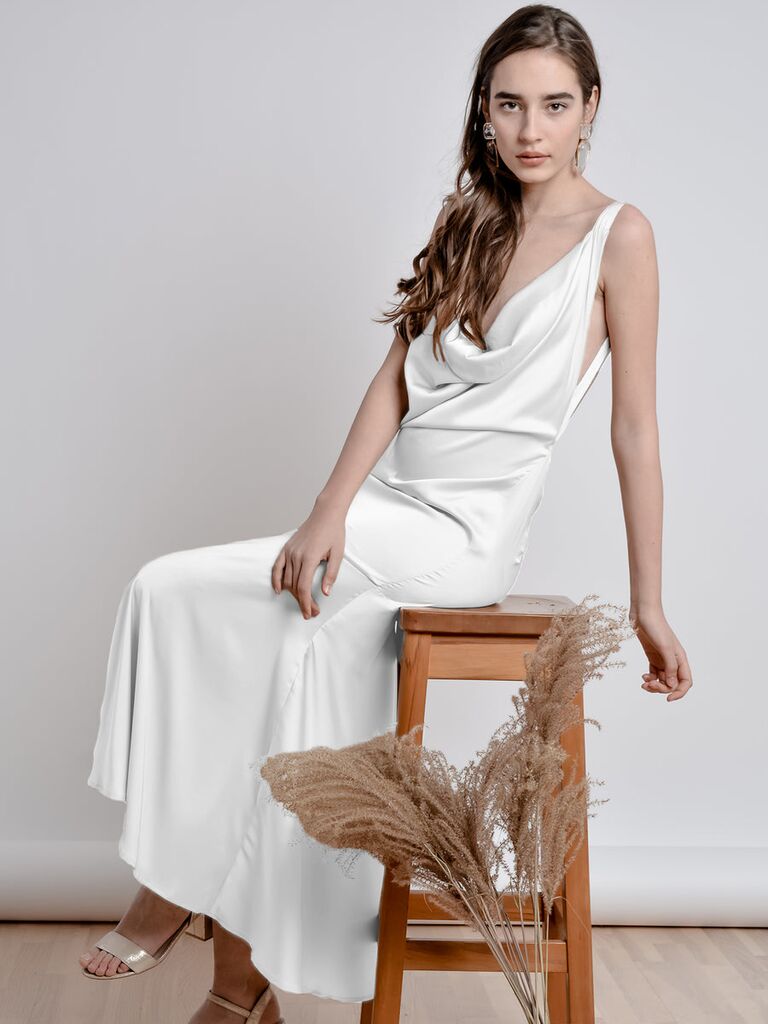 Model wears a white silk gown with a cowl neckline. 
