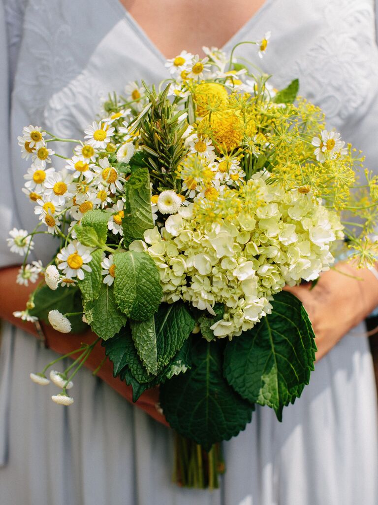A bride holds this white and yellow bouquet.