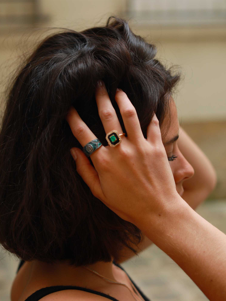 Hexagon emerald center stone with black border and gold pave diamond halo on rose gold band