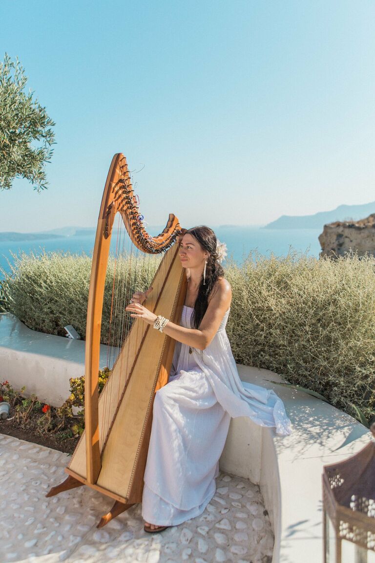 Woman playing harp at oceanside wedding