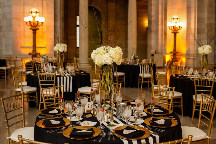 Black and white striped table runners draped over the black tablecloth on the dining table, which was set with gold plates and black napkins. A tall centerpiece of ivory hydrangeas stood in the middle of the table.