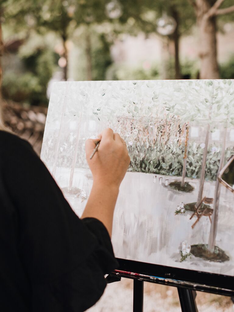2023 wedding reception trend live wedding artist painting a scene of the wedding reception venue onto canvas