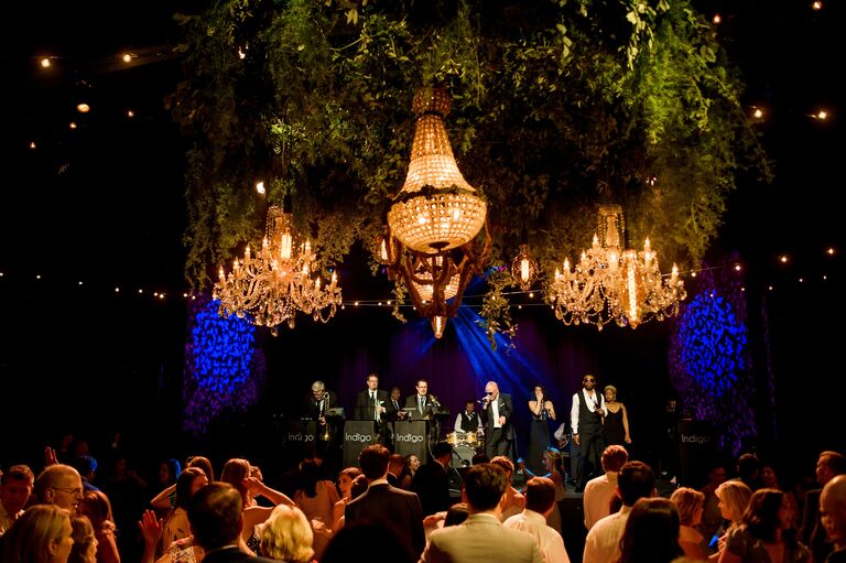 Crystal chandeliers over live band while guests dance at wedding reception