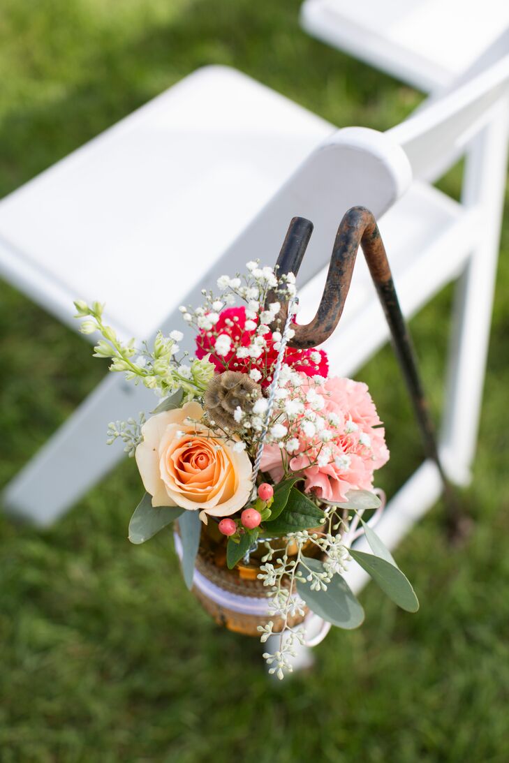 Talia and Casey's wedding day florist, Down The Aisle By Maria, created the unique and beautiful floral arrangements displayed throughout the day. For the ceremony aisle, Maria created small bouquets of various flowers, including roses and baby's breath, and placed them in glass mason jars to hang from hooks.