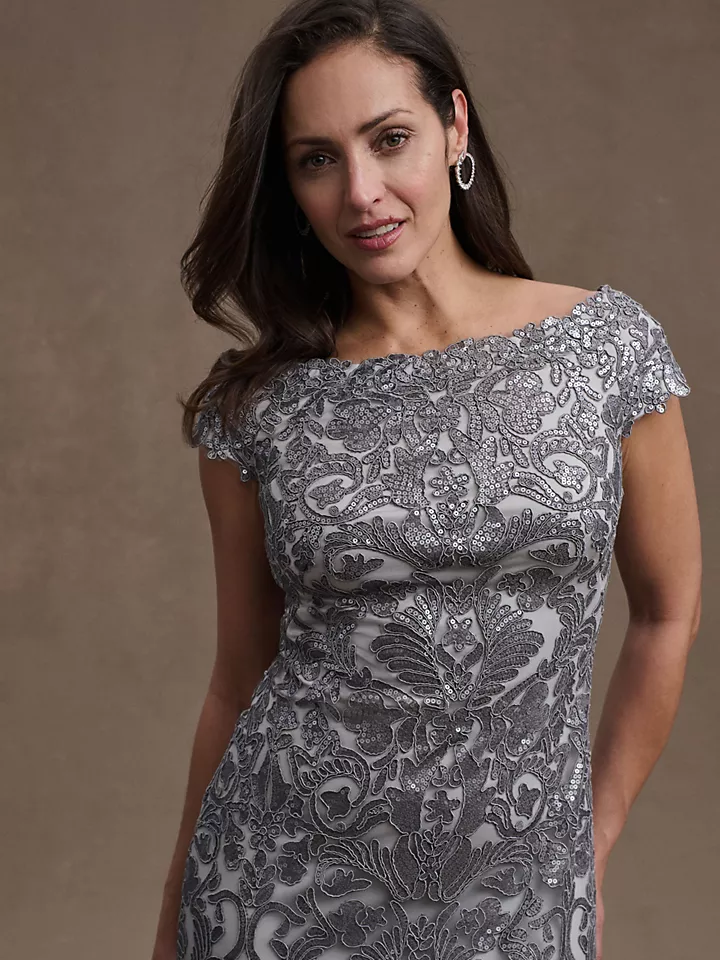 A model shows off this boat-neck silver lace dress with cap sleeves.