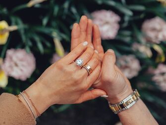 engagement announcement photo with couple holding hands and bride wearing round diamond engagement ring