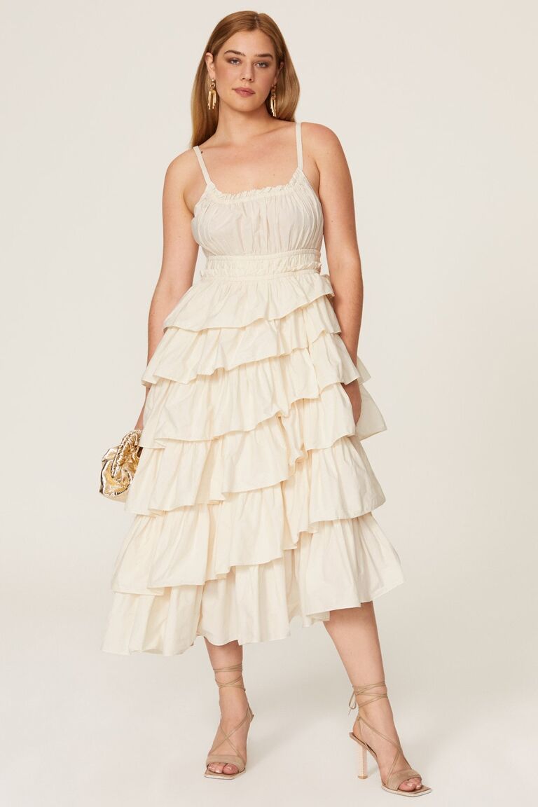 Model wears a ruffled ivory gown. 