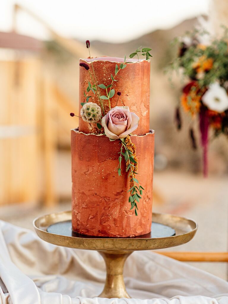 modern fall wedding cake with two tiers painted in terracotta orange color and decorated with mauve rose and greenery