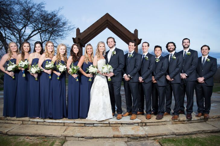 The couple decided on navy groomsmen suits to fit their less-formal style. They also got the groomsmen hand-stamped custom tie clips with their initials. The bridesmaids wore long navy dresses to be comfortable in the winter wind at the rural ranch.