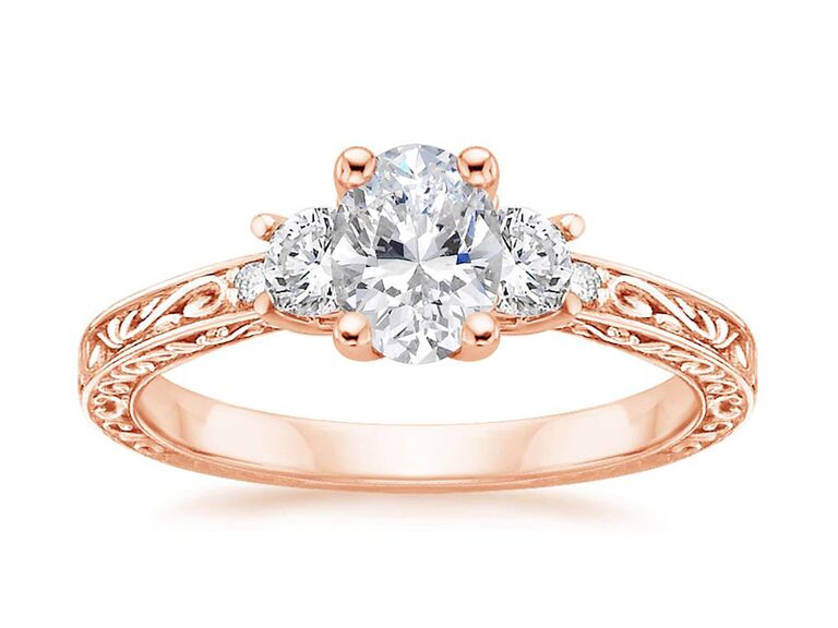 brilliant earth rose gold engagement ring with oval diamond center stone with claw prongs round side diamonds with claw prongs and rose gold trellis band