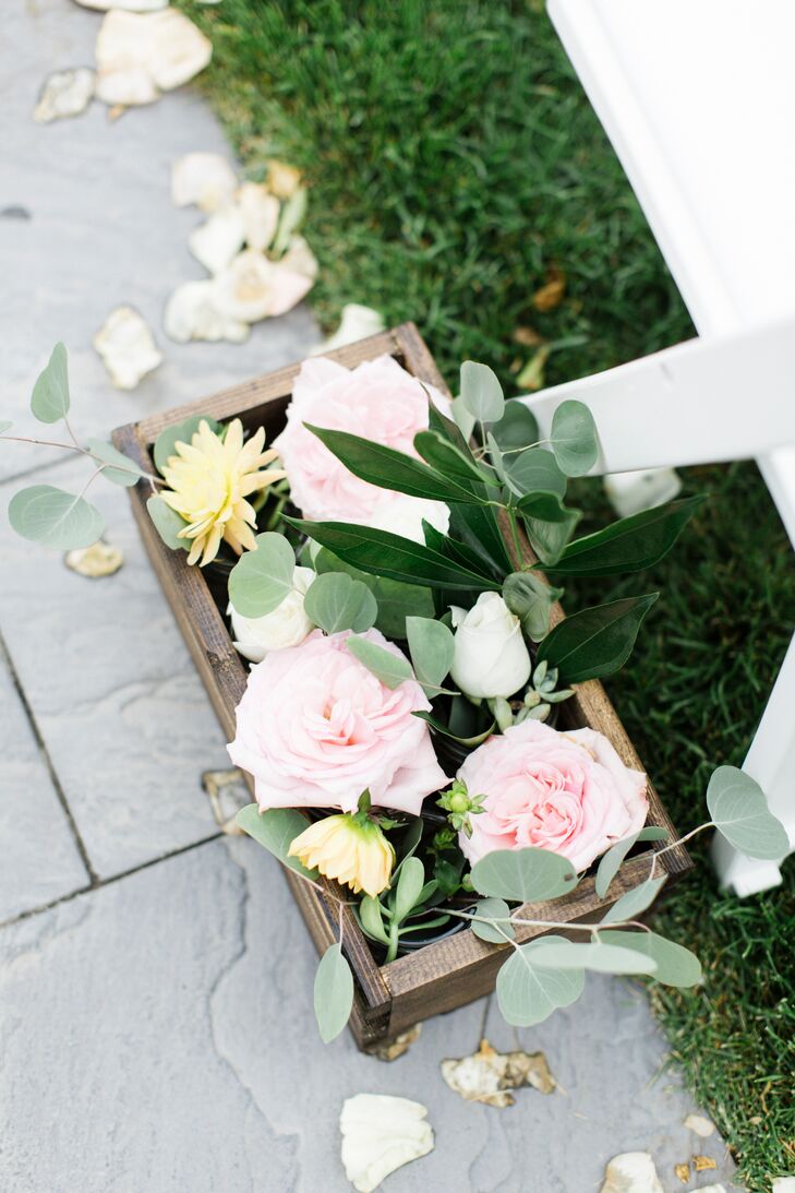 Breakaway boxes made by Daniel marked their ceremony aisle with lush arrangements. Pink roses, blush garden roses, greenery and soft yellow dahlias all filled the pastel display. Rose gold lanterns marked the end of the aisle for a modern touch, highlighting the contrasting garden-style aisle decor and arbor.