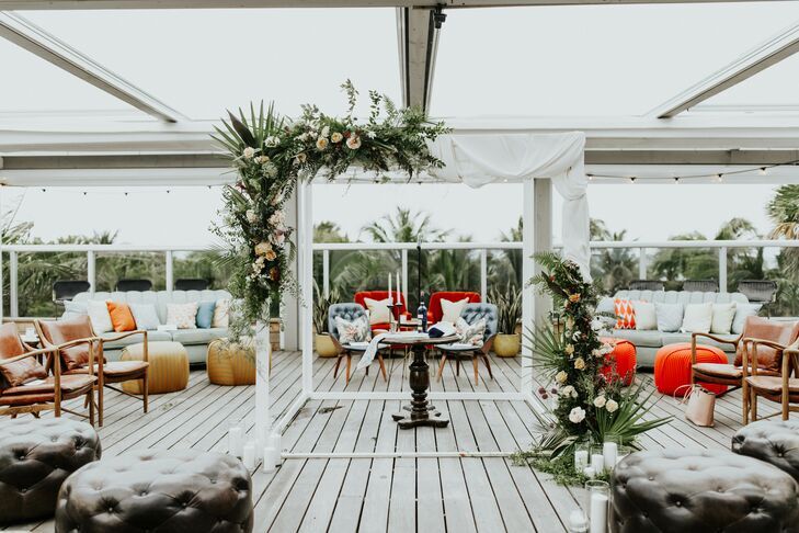 White chuppah with greenery accents at rooftop venue. 