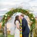 Pam and Caleb shared their first kiss under this fall-inspired wedding arch. It had natural wooden posts with an arch crawling with vines, orange berries and pops of white flowers.