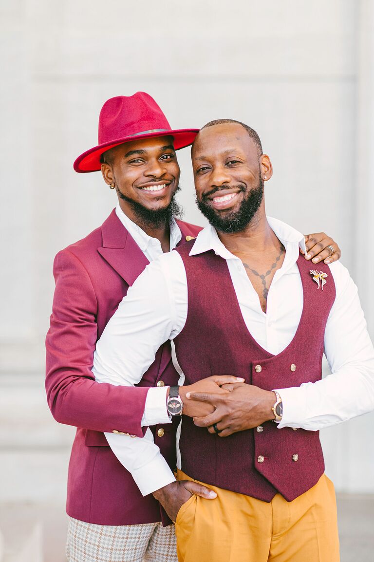 Grooms wearing burgundy suits and holding hands