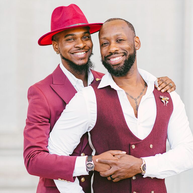 Grooms wearing burgundy suits and holding hands