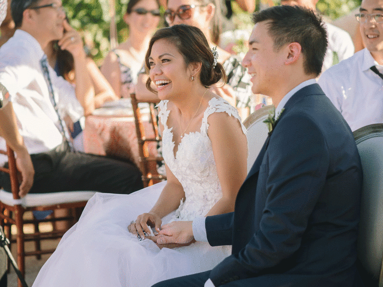 Bride and groom sit and smile while looking at love story slideshow.