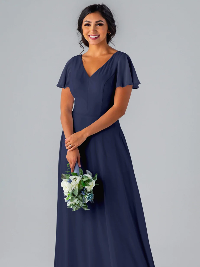 A model shows off a gorgeous floor-length gown with delicate ruffled sleeves and a V-neckline.
