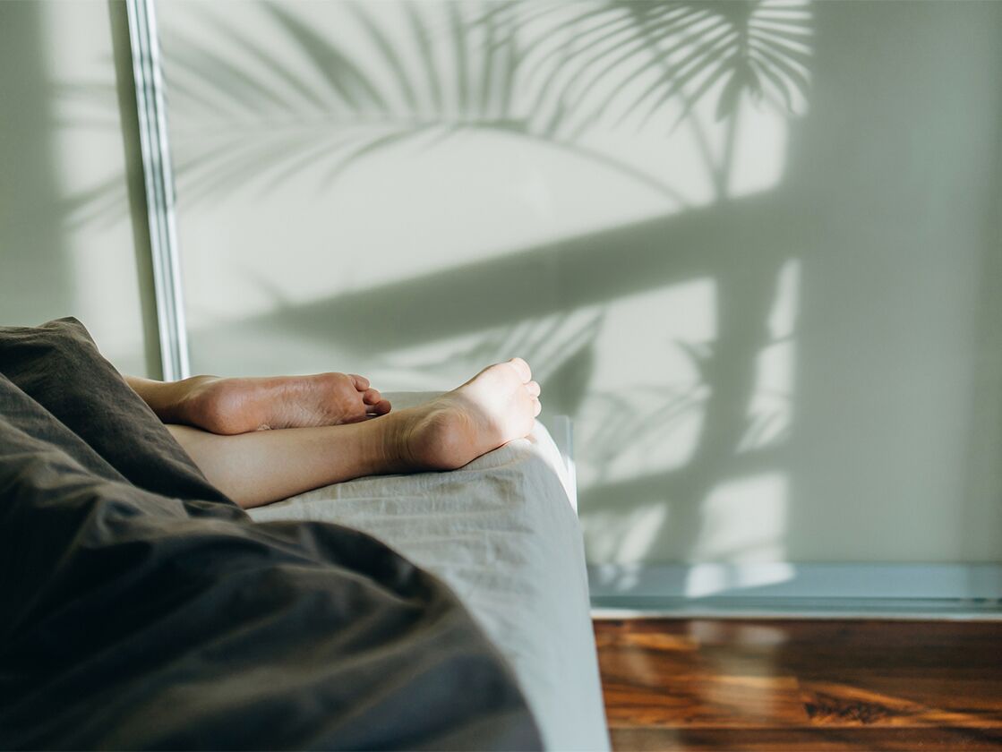 Person's bare feet lying on bed