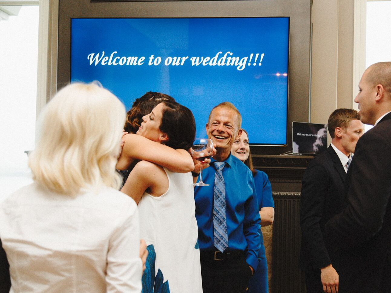 Bride and guests embracing at a surprise wedding