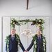 Grooms on Wedding Day Next to Custom Signage