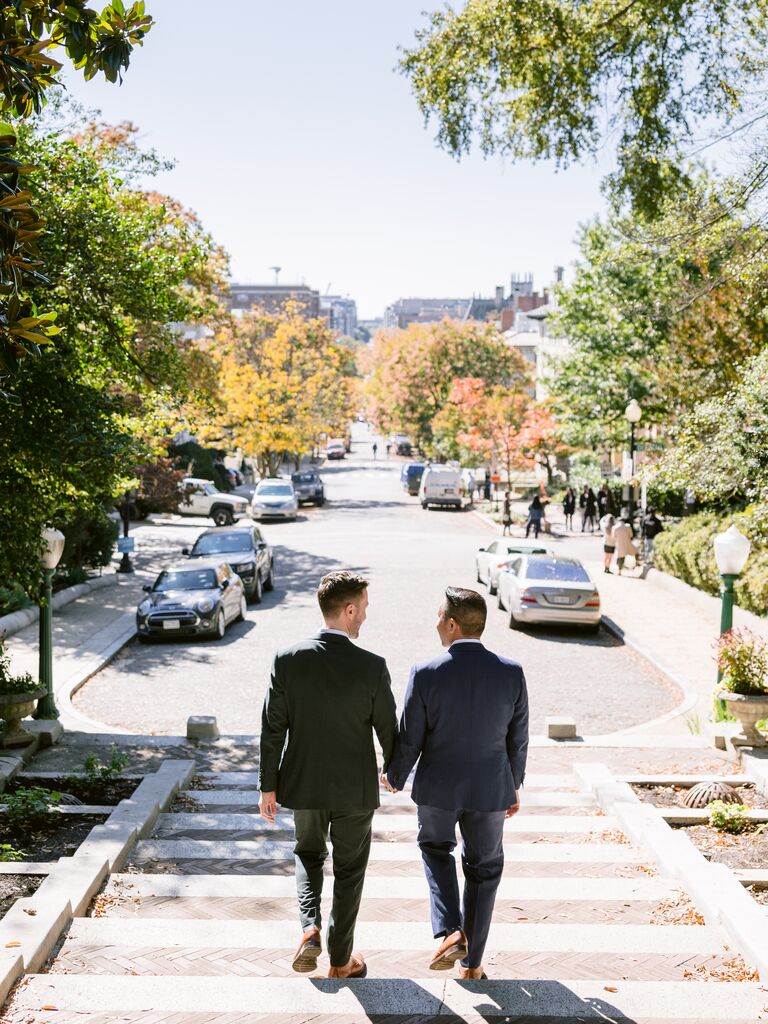 Two men hold hands as they walk down the stairs in this engagement photo