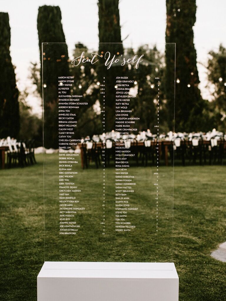minimalist acrylic wedding seating chart with names written in white calligraphy