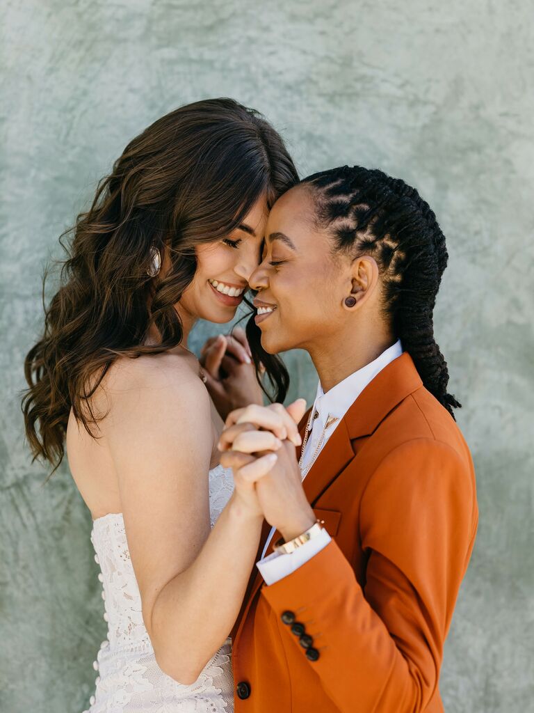 Couple hold hands and face each other while smiling. 