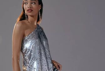 Model wears a long shimmery silver dress while looking over her shoulder. 
