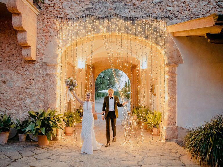 Bride and groom entering reception through string light curtain.