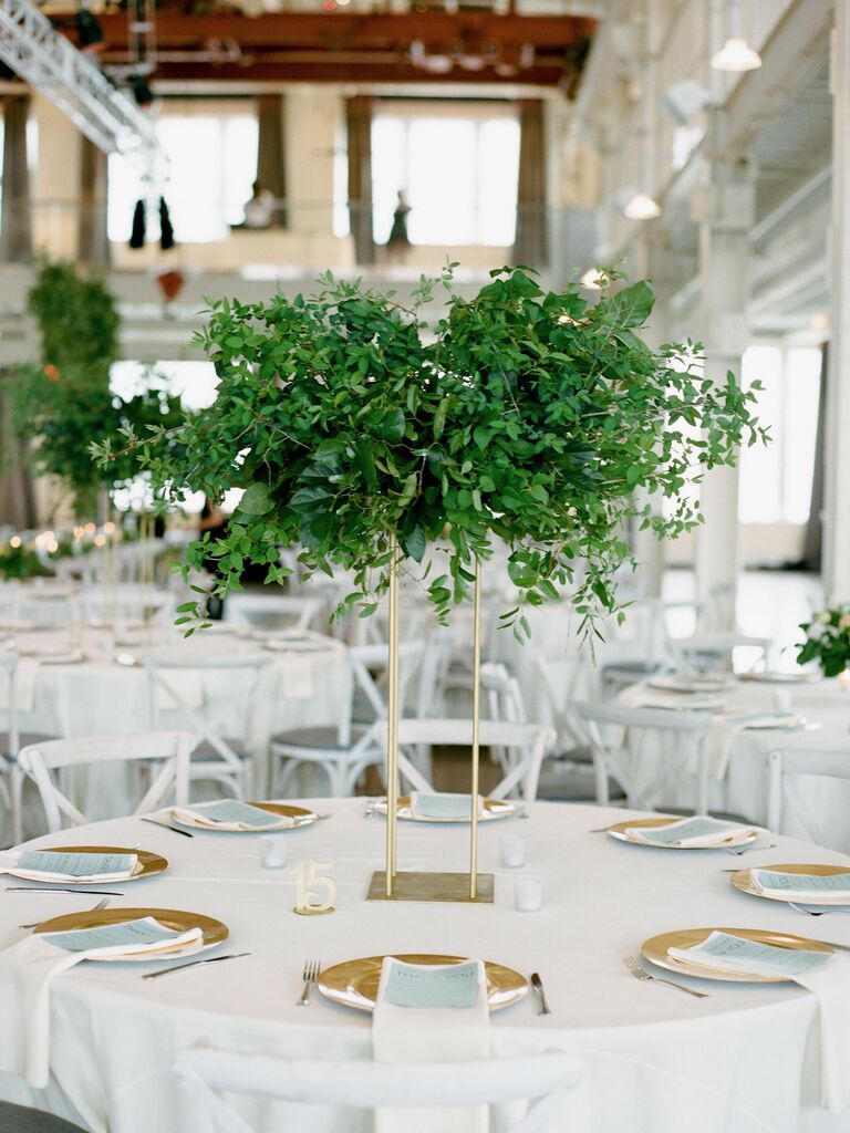 simple tall wedding centerpiece with greenery on square gold pedestal stand
