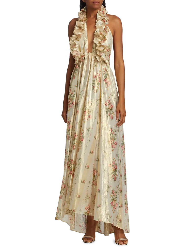 Model wears a whimsical sleeveless dress with a halter neck and a floral pattern. 