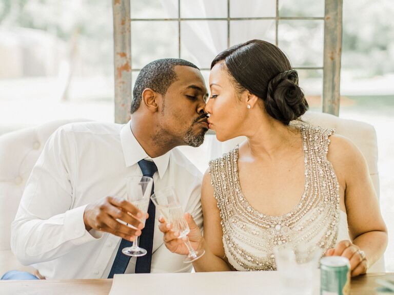 Couple share a sweet kiss while toasting champagne at their vow renewal. 
