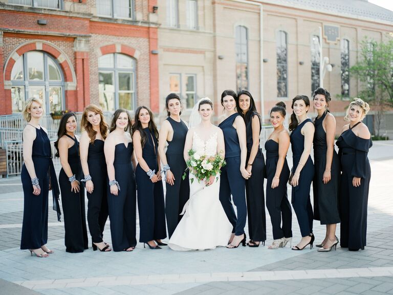 bride stands next to bridesmaids in mix-and-match navy blue jumpsuits