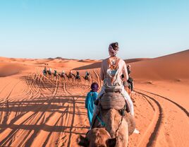 Girl riding a camel in Sahara Desert Morocco. Camel expedition in the desert.