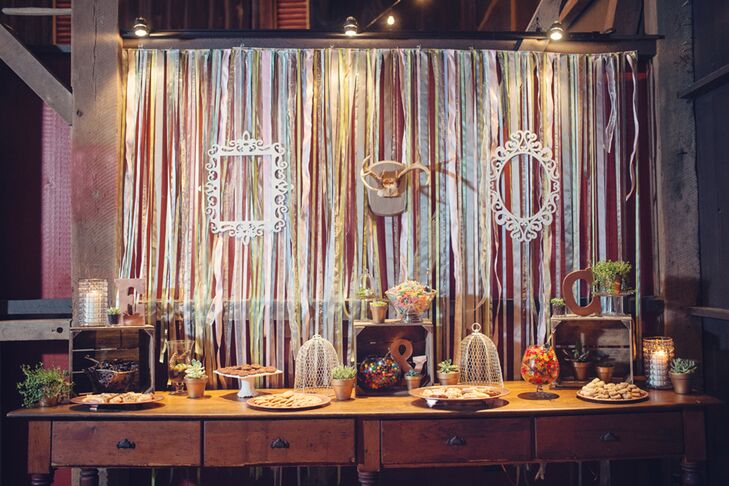 In lieu of a traditional wedding cake, Erin and Cory had a candy bar fit for a photo opp! Dogwood Events accented a vintage wooden desk with tiered baked goods, cookies and glass bowls filled with candy. Streamers, vintage-style frames and antlers formed the backdrop for an unexpected touch.