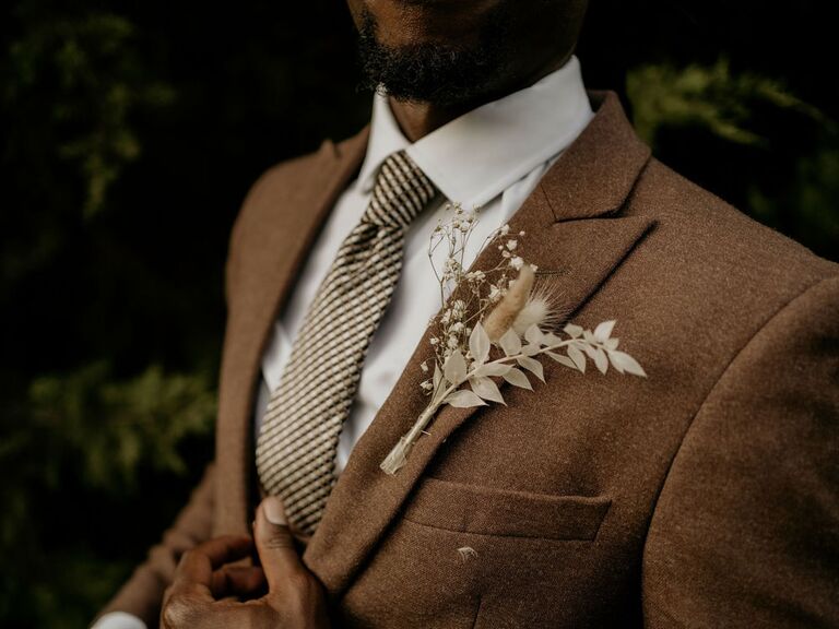 Groom wearing brown suit with boho dried flower boutonniere