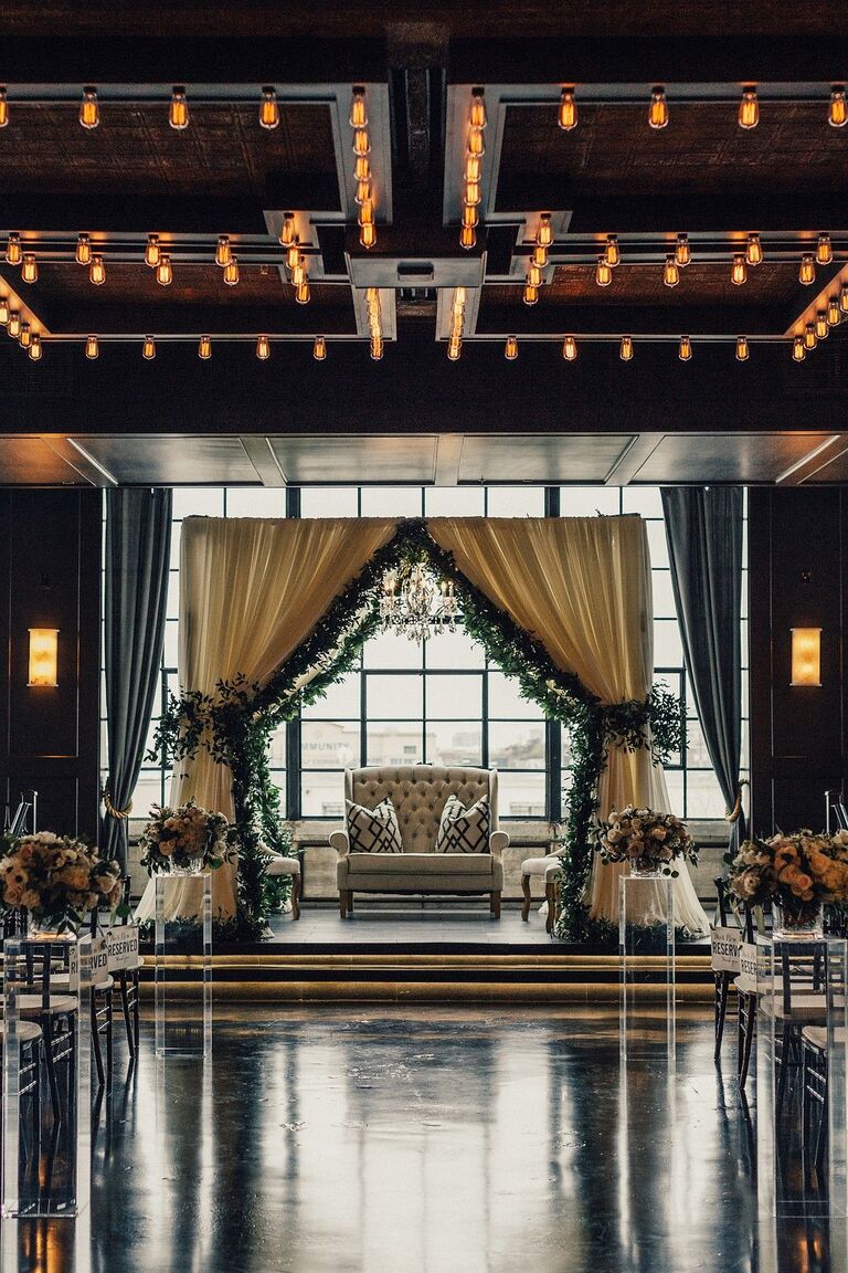 Mandap with cream draping and greenery garland accents