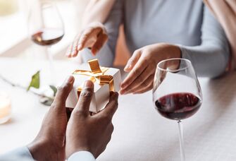 Husband giving wife five-year anniversary gift at dinner 