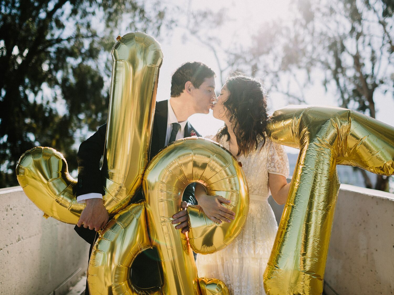 couple kissing and holding letter balloons