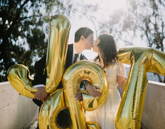 couple kissing and holding letter balloons